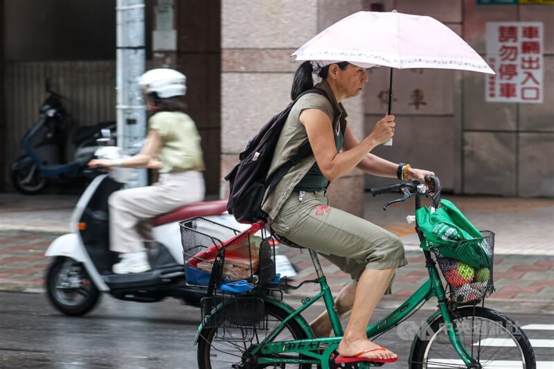圖為台北市民眾撐傘騎自行車。中央社記者鄭清元攝 113年4月30日