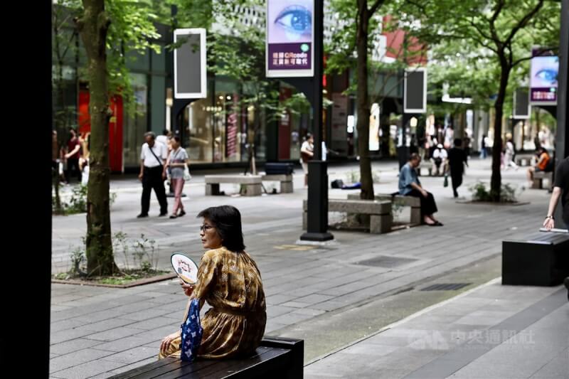 台北市信義區民眾坐在騎樓下乘涼，搧風消暑。中央社記者翁睿坤攝 113年6月10日