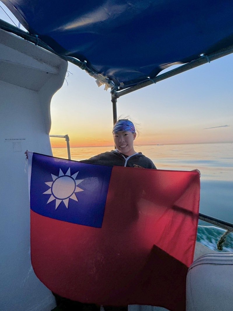台灣海泳女子好手許汶而克服低溫、洋流、水母等，完成單人泳渡英吉利海峽的壯舉，成為台灣史上第一人，她上岸後開心拿著中華民國國旗拍照留念。（許汶而提供）中央社