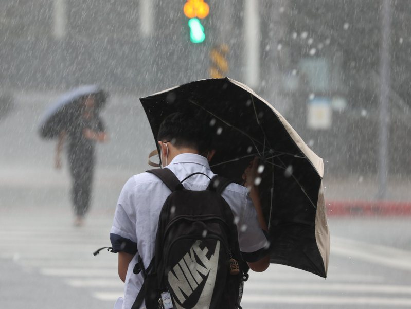 中央氣象署今天下午發布颱風強風告警，這也是今年第一次發布強風告警。圖為民眾在風雨中喫力行走。記者林澔一/攝影