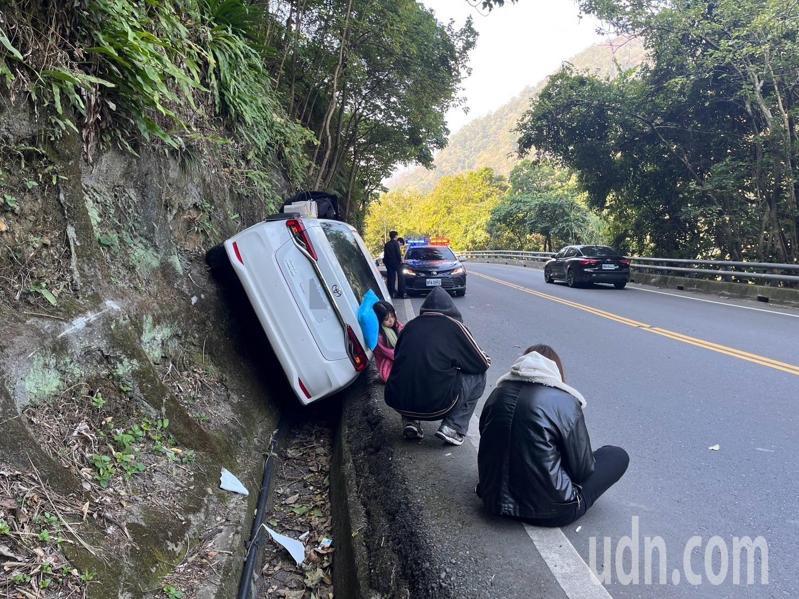 4名年輕人到武嶺追雪，下山時黃姓駕駛疑似睡著，轎車衝到對向車道，4輪騎上山壁，4人蹲在路旁餘悸猶存。圖／